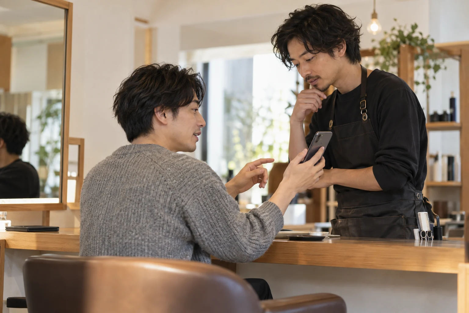 参考写真を見せながら理美容室で髪型を相談する男性のイメージ